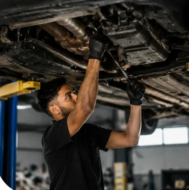 Mechanic inspecting the underside of a vehicle